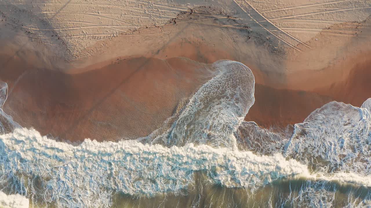 vista aérea de las olas que se estrellan en una playa de arena