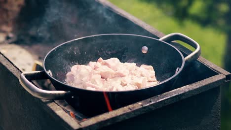 close-up slow motion pork meat is fried in saucepan on charcoal