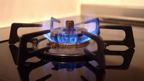 Close-up-of-a-gas-stove-gas-burner-turned-on,-lowered,-and-eventually-turned-off