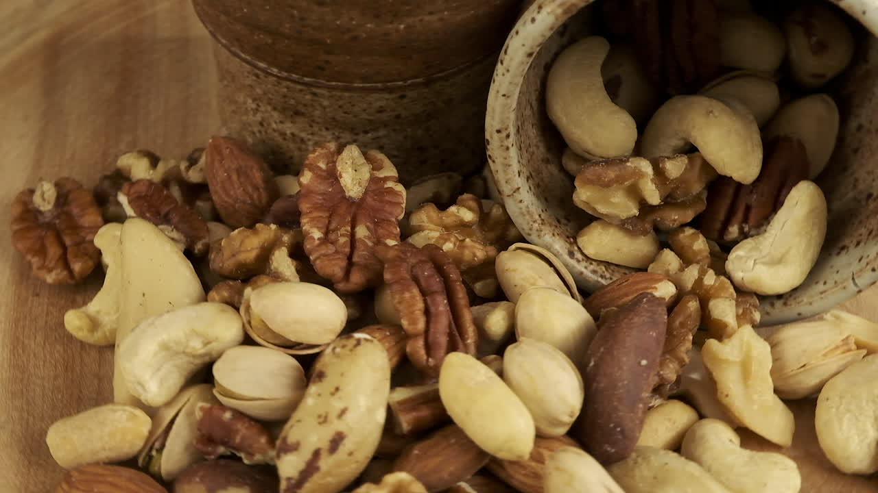 Rich golden nuts piled onto wooden platter rotate in close up view