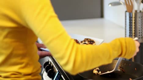 Woman-preparing-grapes-tart-and-man-using-digital-tablet-in-kitchen