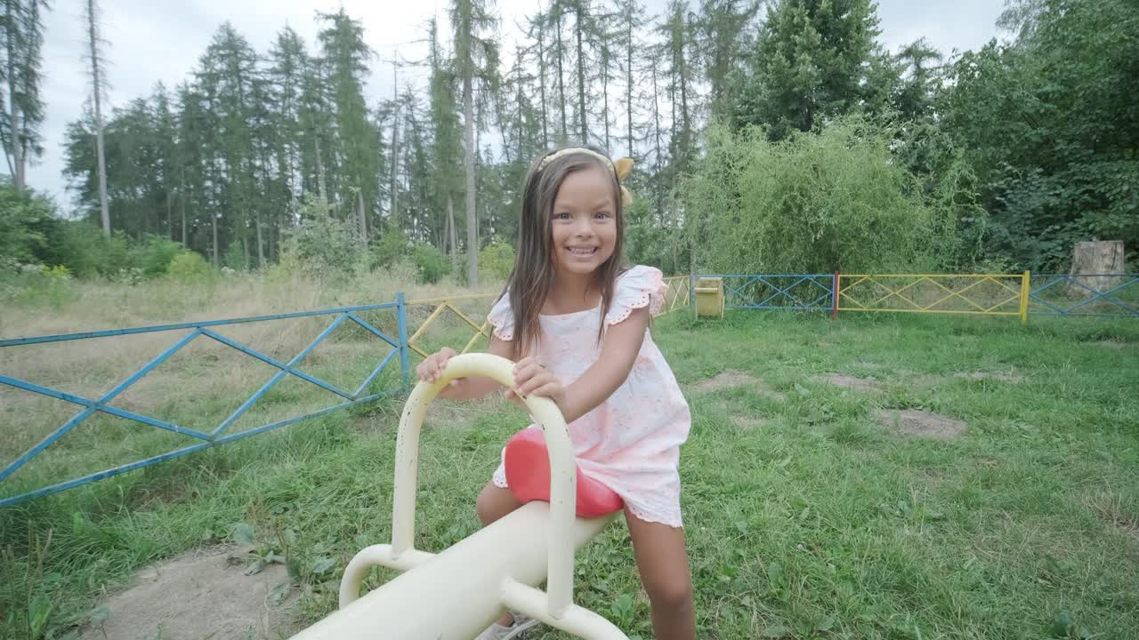 una madre embarazada y su hija joven disfrutan de un tiempo de juego juntos en un patio de recreo en el parque, rodeados de árboles y vegetación