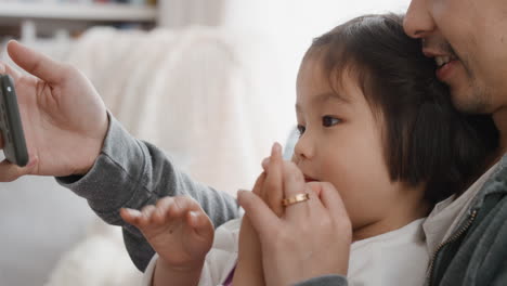 아시아의 아버지와 자녀가 스마트폰을 사용하여 비디오 채팅을 하고 있습니다. 작은 소녀는 주말을 공유하고 있습니다. 아빠와 함께 휴대폰으로 친구 4k와 채팅을 즐기고 있습니다.
