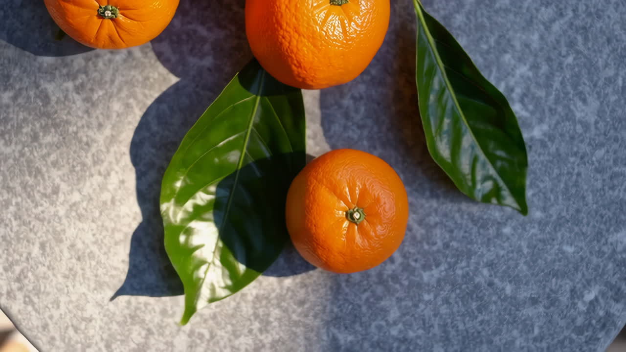 Oranges with Green Leaves on a Grey Surface