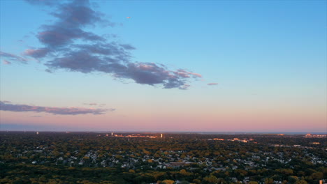 high-altitude-hyper-lapse-of-a-rich---colorful-sunset,-over-a-green-tree-filled-suburban-neighborhood-in-New-York