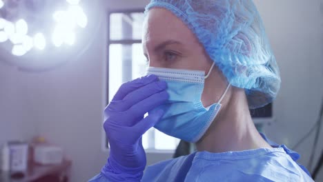 female caucasian surgeon with face mask, surgical cap and protective clothing in hospital