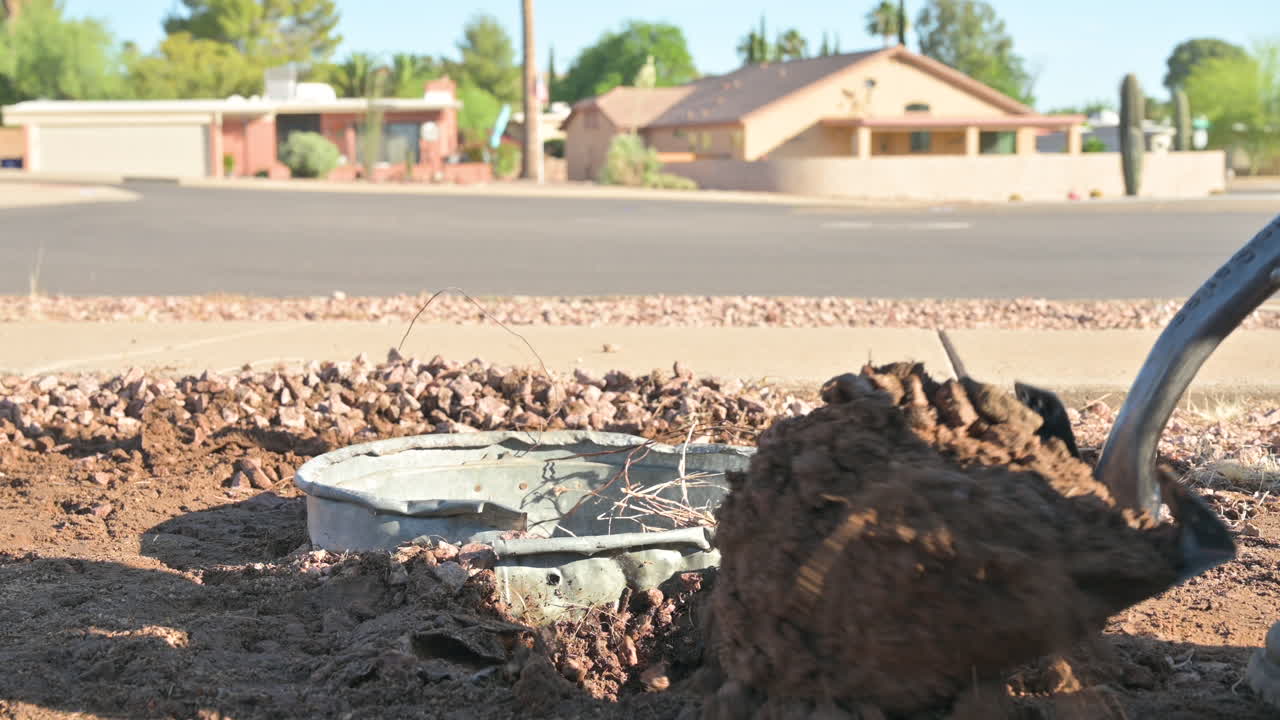 primer plano de botas pisando una pala para excavar un receptáculo de basura en el suelo, común en green valley, arizona, para disuadir a la vida silvestre de robar la basura