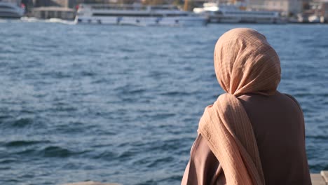 mujer en hijab mirando al mar