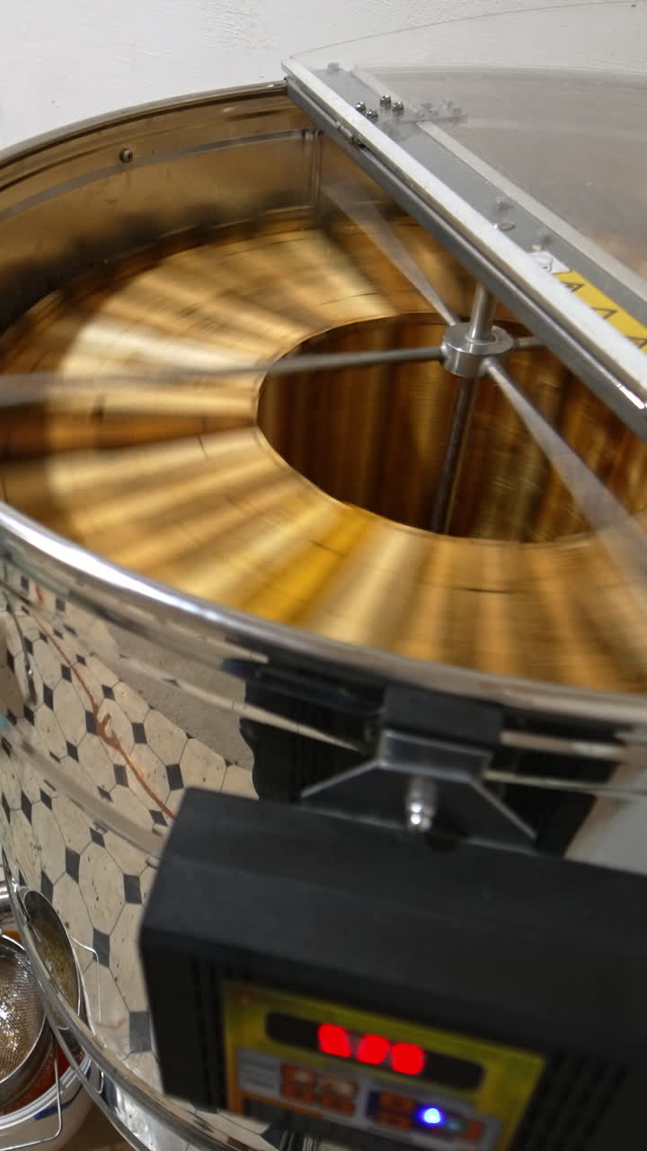Automatic electric appliance for honey extraction working at the apiary. Big metal box full of frames standing beside. Vertical video