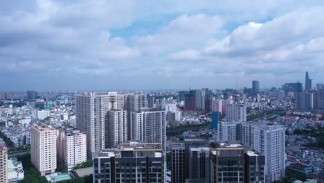 aerial crane shot of ho chi minh city skyline to ground level old iron and wood shacks, traditional river boats and ultra modern high-rise buildings on sunny day