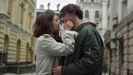 man kissing woman's nose on street.