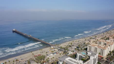 sweeping drone view of oceanside, california with pier in background