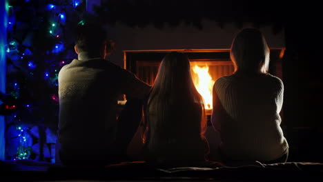 family resting by the fireplace and christmas tree