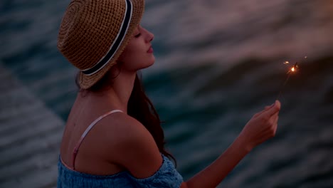 young woman on summer holidays holding sparklers at the sea