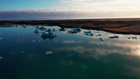 flying over the icebergs of the jokusarlon glacier lagoon, south east iceland on a clear sunny morning - aerial shot