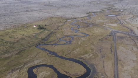 River-meandering-through-vast-open-tundra-in-Iceland,-aerial