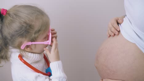 girl-in-glasses-plays-doctor-with-pregnant-mommy-in-room