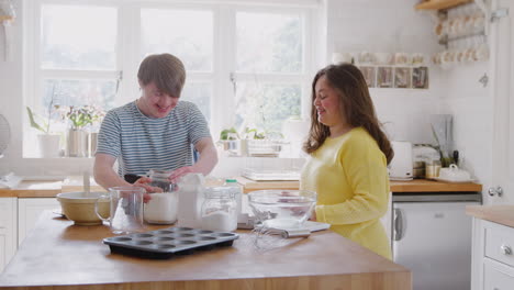 pareja joven con síndrome de down midiendo ingredientes para hornear pastel en la cocina en casa