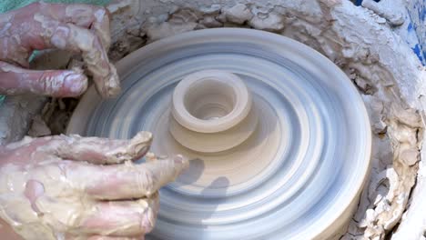 potter's hands work with clay on a potter's wheel