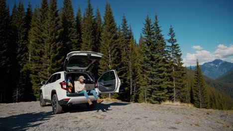 digital nomad working from car trunk in mountains