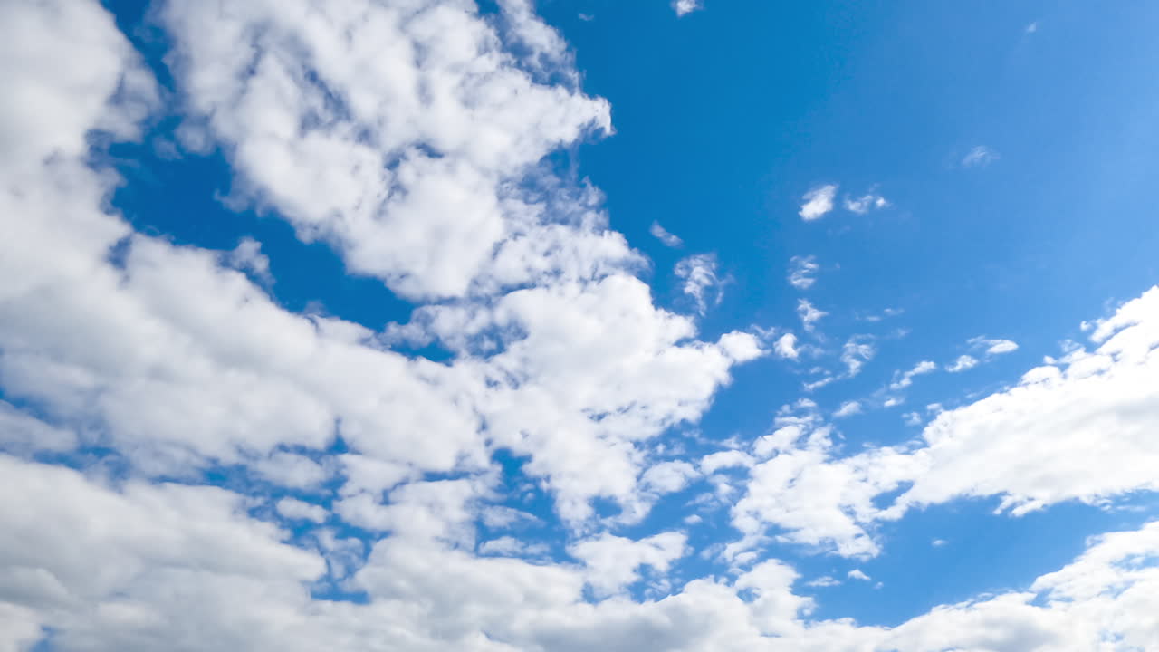 Soft white cloudscape moving by the azure horizon. Beautiful low angle view of sky on sunny day covering with light clouds. Timelapse.