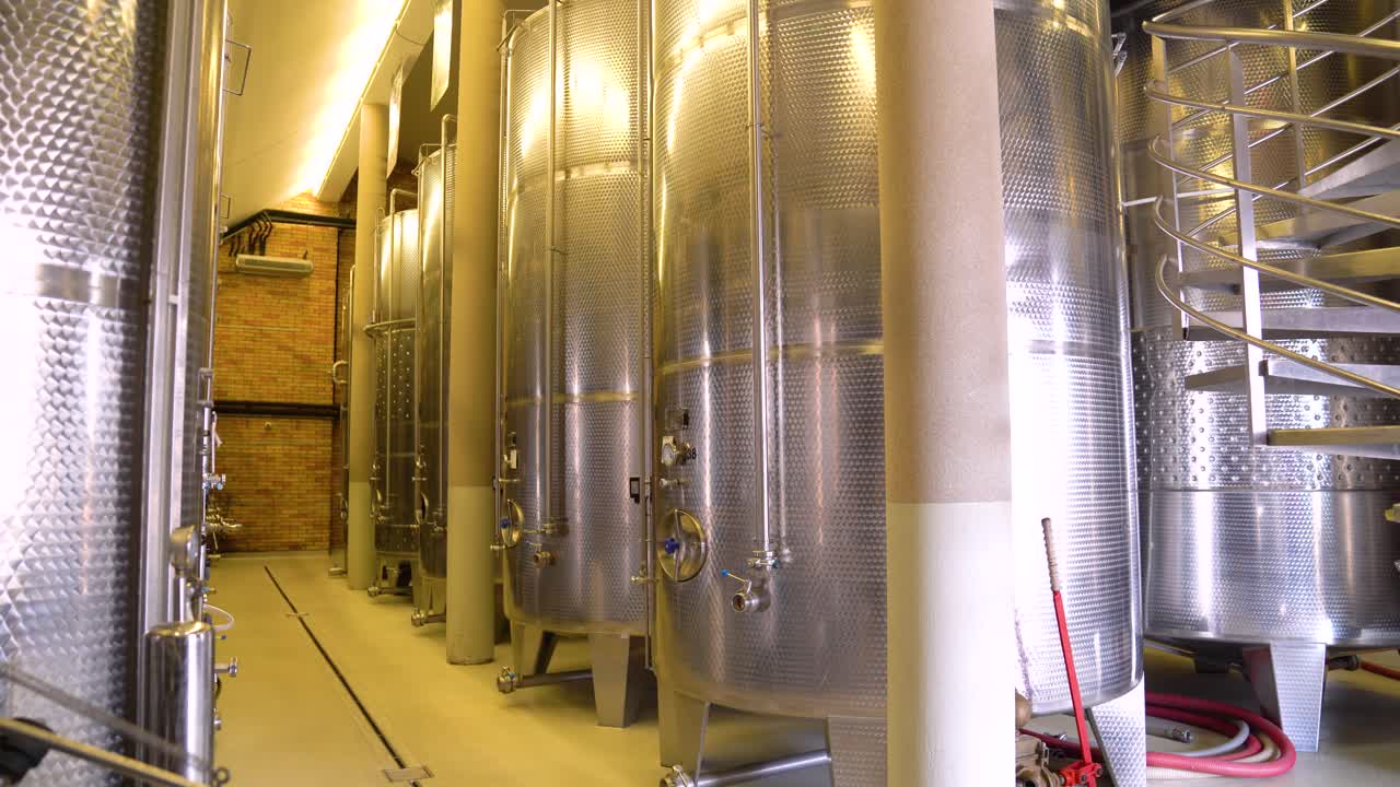 este video captura una vista panorámica de una bodega de vino con grandes barriles de acero que almacenan vino