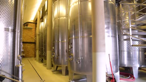 This-video-captures-a-panoramic-view-of-a-winery-wine-cellar-with-large-steel-barrels-storing-wine