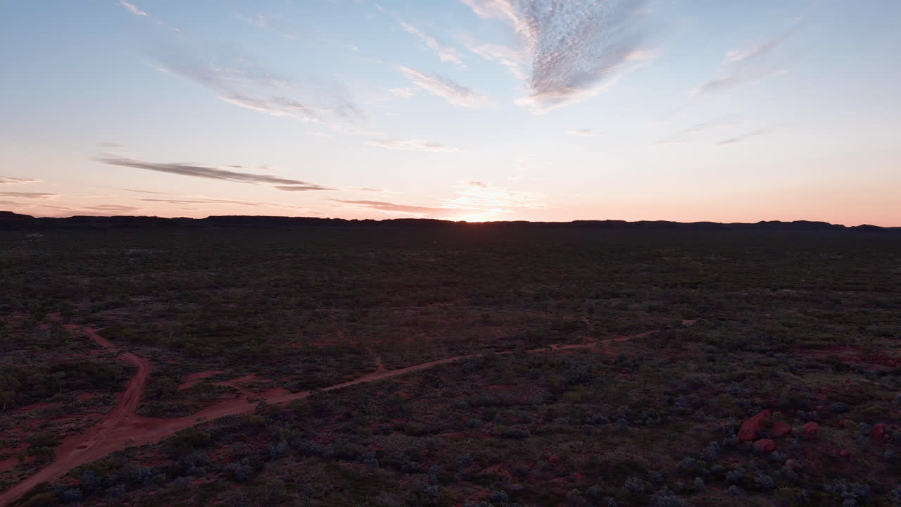 pista de vuelta, inclinar hacia arriba, puesta de sol sobre las colinas del interior del monte isa con una bifurcación en el suelo rojo camino de tierra, cielo azul y naranja con nubes de plumas y llamaradas de lente