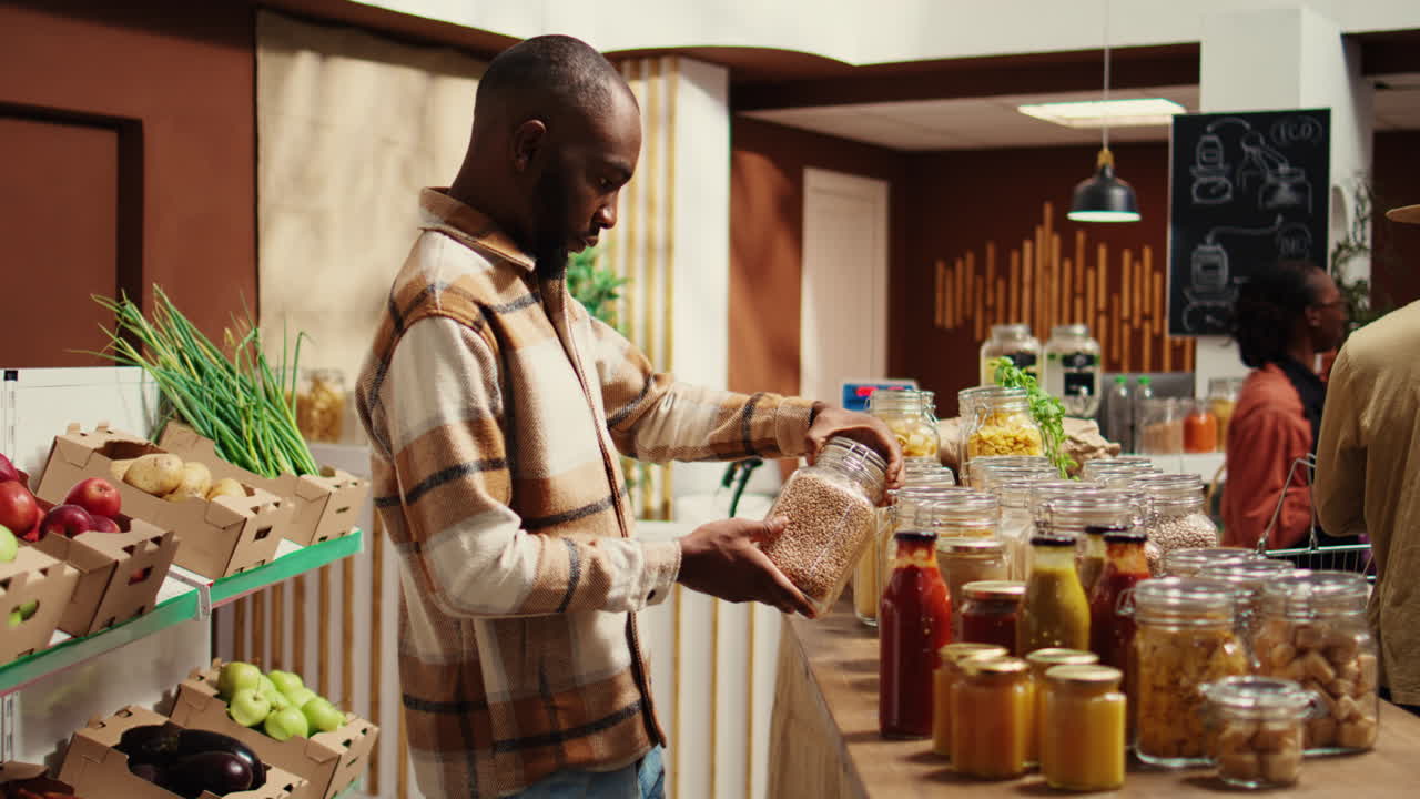 Male customer checking types of pasta or grains at local market