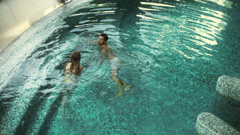 Above-view-of-happy-couple-swimming-in-pool.-Beautiful-couple-relaxing-in-pool