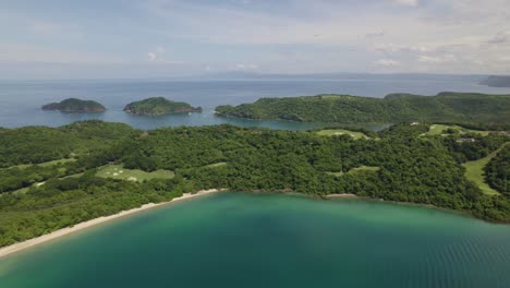 Paneo-Aéreo-A-La-Derecha-De-La-Costa-Verde-De-La-Selva-Tropical-Y-El-Mar-Turquesa-En-La-Playa-De-Nacascolo-En-Un-Día-Nublado,-Península-De-Papagayo,-Costa-Rica