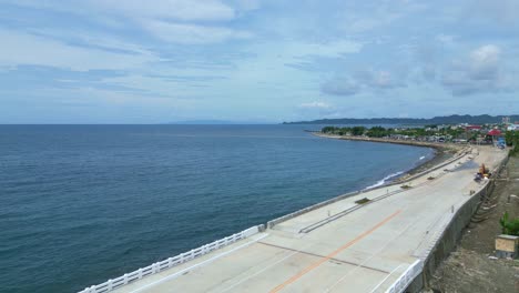 Aerial,-Establishing,-Drone-Shot-of-Beautiful-Ocean,-bridge-and-Seawall-facing-Coastal-Barangay-in-Virac,-Catanduanes,-Philippines,-Asia