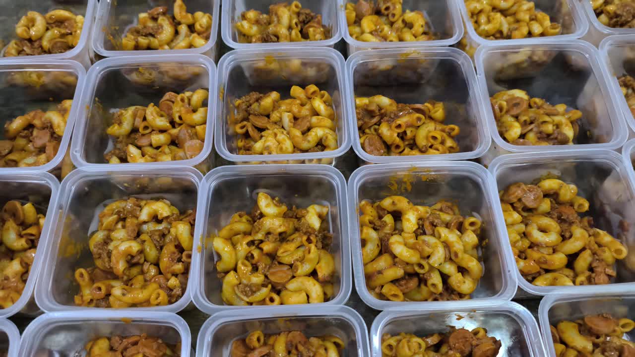 Cooked macaroni is portioned into small, equal containers. This method simplifies division, serving, or preparation for sale