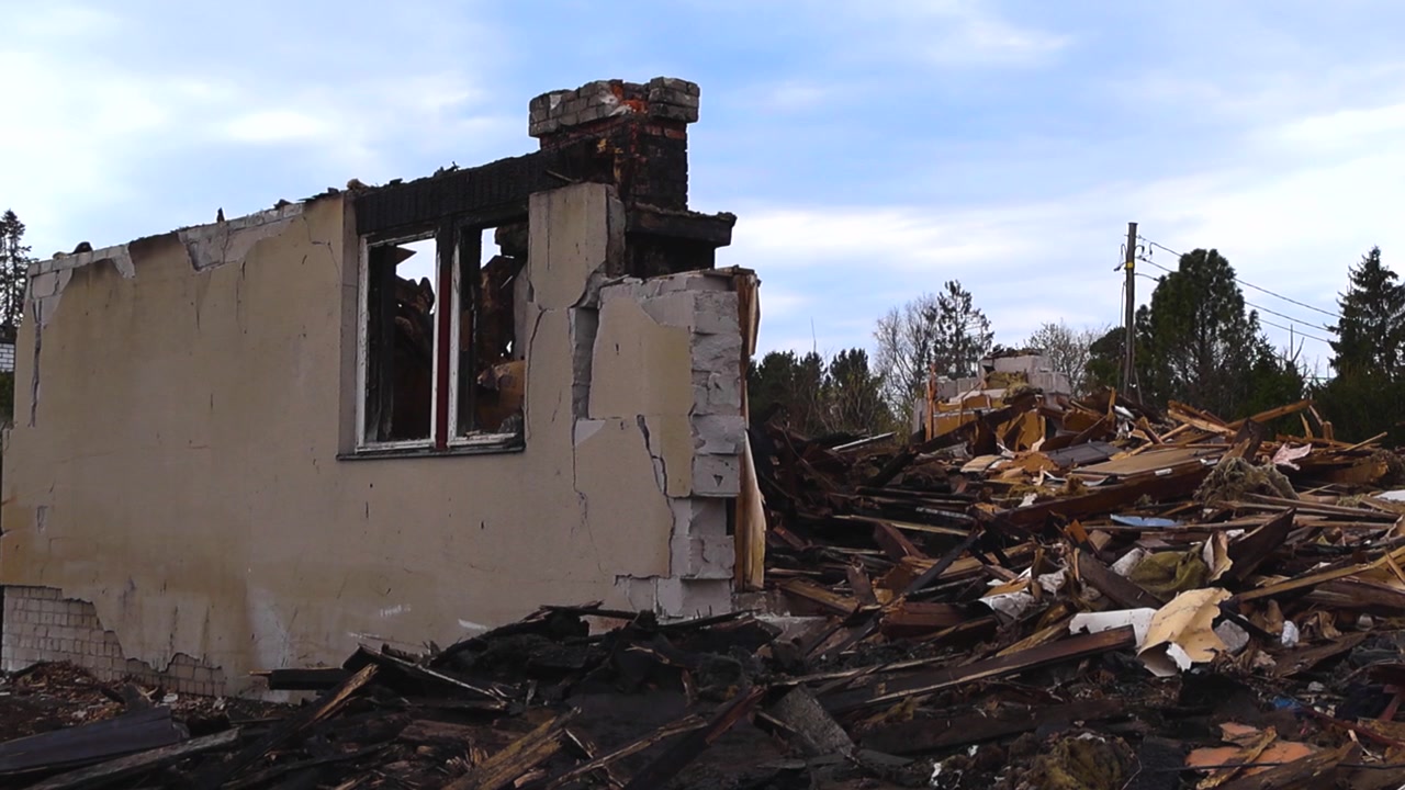 Edificio in rovina con un camino bruciato e muri rotti circondato da un grande cumulo di macerie e detriti della demolizione, concetto di conseguenza di un disastro o di degrado urbano