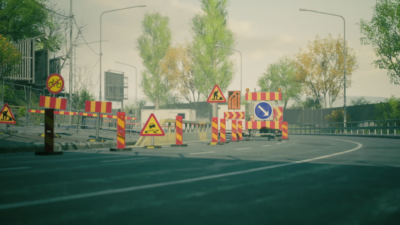 Road construction in urban area with warning signs and barriers in fall