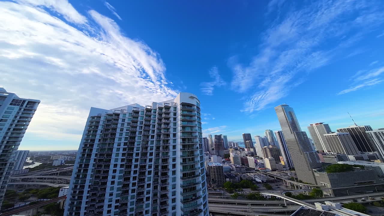 Beautiful high-rise buildings in the panorama of American city. FPV drone footage above the river approaching the multi-storied house.