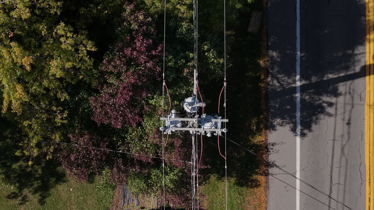 Aerial view of a transformer and power lines by a road