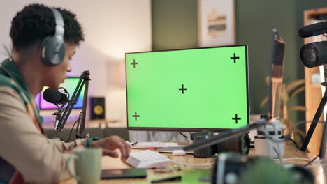 content creator at their workstation with a green screen