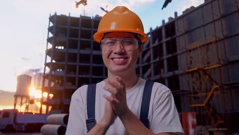 trabajador asiático aplaudiendo sus manos en el sitio de construcción