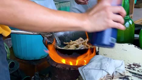 close up shot hand of man cooking indonesian street food using traditional fireplace