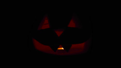 happy halloween creepy jack o' lanterns glowing in the dark wishing happy halloween: carved pumpkin decorations with burning candles inside.