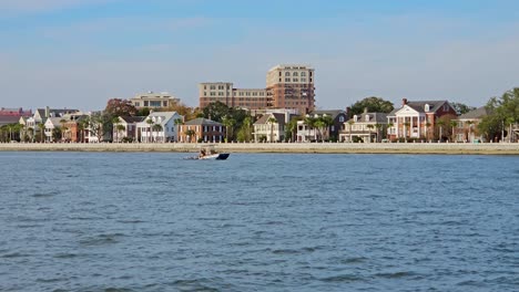 barco de cangrejo rodeado de pelícanos con la costa de la ciudad de charleston en el fondo