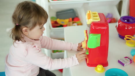 niña de 3 años jugando con coloridos juguetes de plástico en casa - vista de perfil