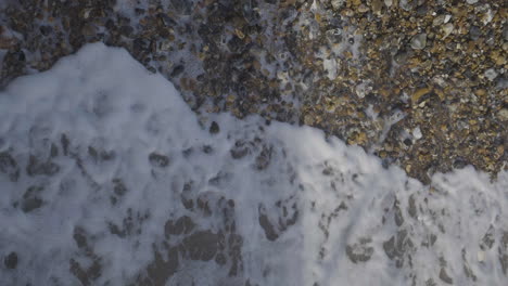 Wellen,-Die-Am-Steinigen-Strand-Ein--Und-Ausgehen,-Vogelperspektive