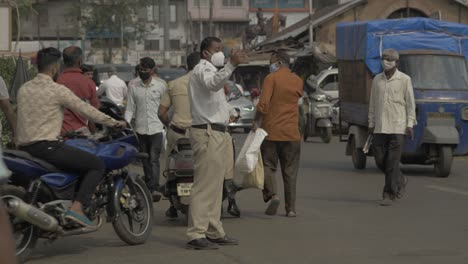 an indian traffic police officer manages the traffic during the market hours before the curfew of second wave lockdown during the covid pandemic.