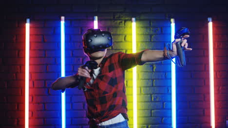 young woman in vr glasses and using joystick while playing a virtual reality game in a room with colorful neon lamps on the wall 1