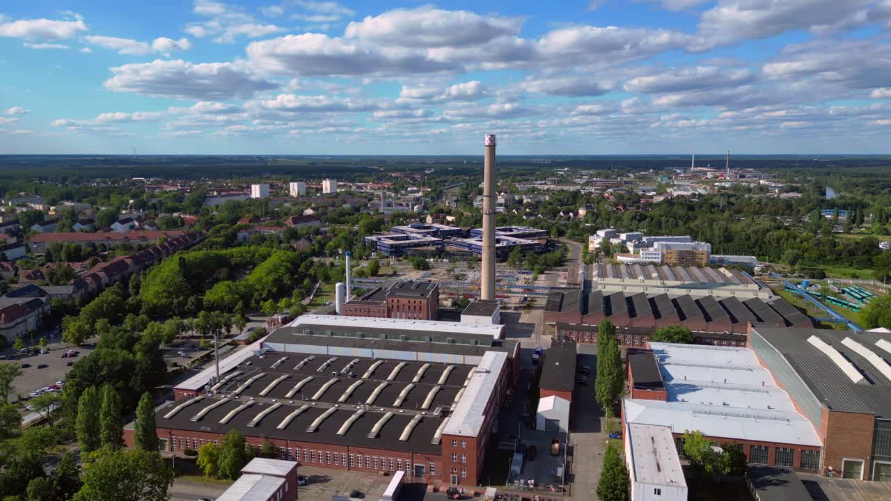 industrial buildings and a chimney in Hennigsdorf, Germany, with a train passing by. Gorgeous aerial view flight static tripod hovering drone