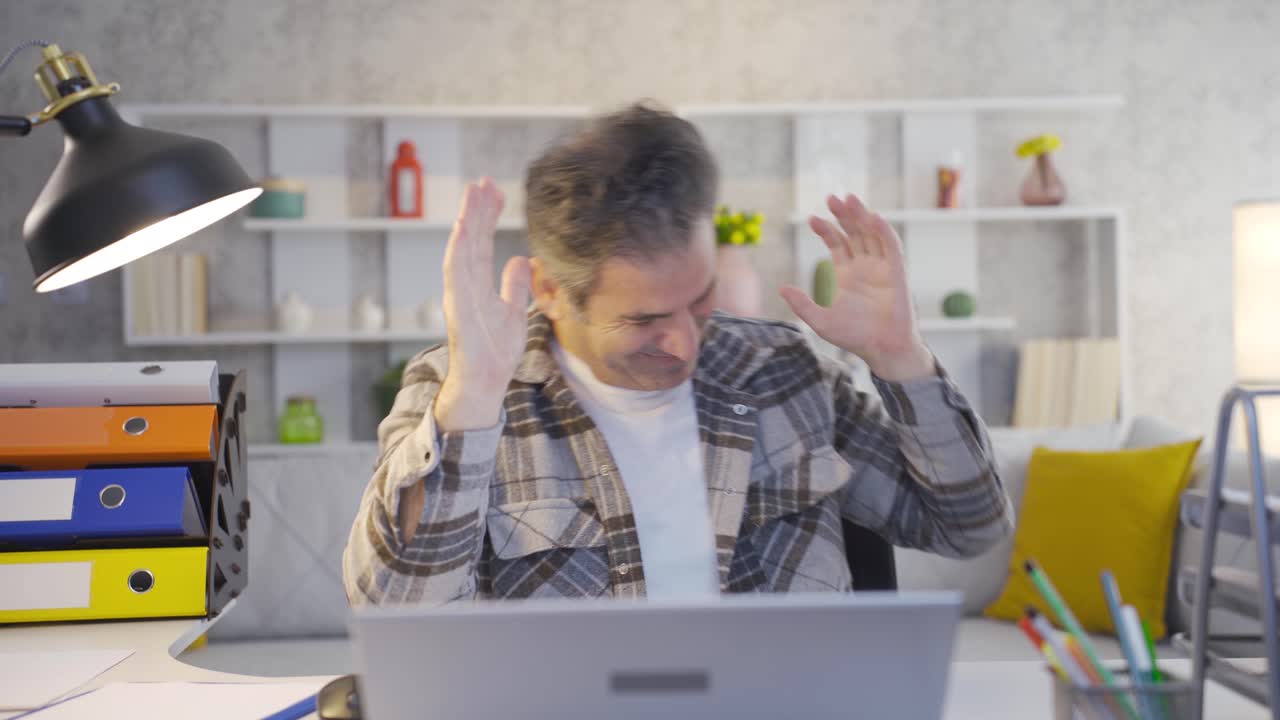 un trabajador maduro de la oficina en casa usando una computadora portátil con emoción y alegría está bailando, recibiendo buenas noticias.