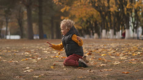 Niño-Feliz-Está-Jugando-En-La-Naturaleza-En-El-Parque-En-El-Día-De-Otoño-El-Niño-Está-Sentado-En-El-Suelo-Caminando-El-Fin-De-Semana-El-Bebé-De-Infancia-Feliz-Se-Está-Divirtiendo