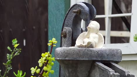 ángel de cerámica sobre una bomba de agua bajo la lluvia